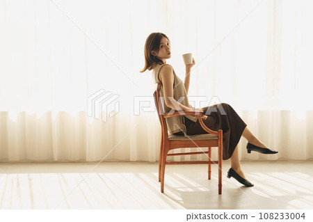 A woman drinking coffee at the window 108233004
