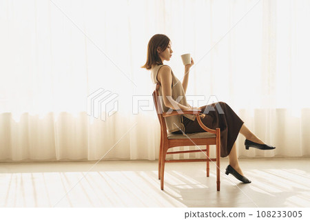 A woman drinking coffee at the window 108233005