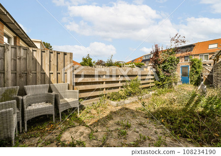 an abandoned house in the middle of a small town with weeds growing on the ground and fenced off to the side 108234190