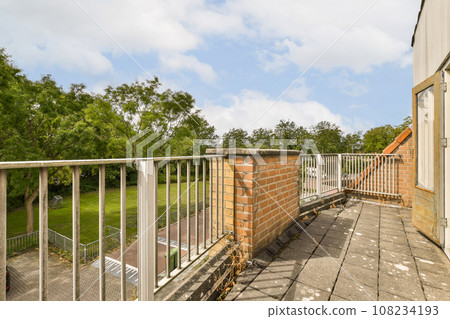 a balcony with some trees in the background and an open door to another room on the other side of the building a balcony with some trees in the background and an open door to another room on the other side of the building 108234193