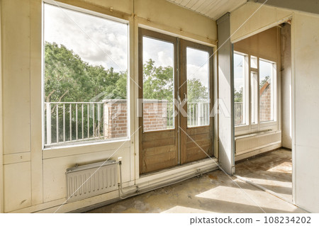 an empty room with two windows and no one on the wall, but there is a view of trees outside 108234202