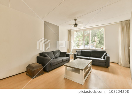 a living room with two couches and a coffee table in front of a large window looking out onto the street 108234208