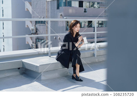 Business woman taking notes on the rooftop Business woman taking notes on the rooftop 108235720