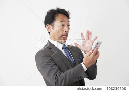 Surprised middle-aged businessman looking at his smartphone, white background 108236808
