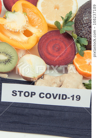 Inscription stop covid-19, fresh fruits with vegetables and protective mask Inscription stop covid-19, fresh fruits with vegetables and protective mask 108237189