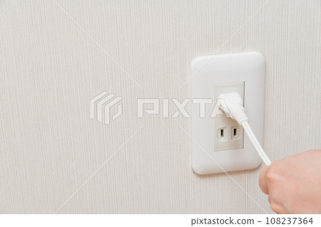 [Bad example of unplugging the outlet while holding the cord] 108237364