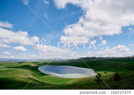 Vrazje lake in the shadow of clouds in a green valley. Durmitor, Montenegro Vrazje lake in the shadow of clouds in a green valley. Durmitor, Montenegro 108237474