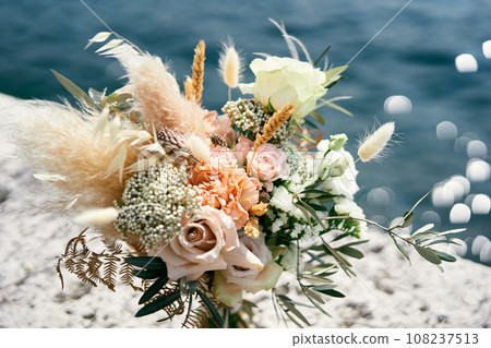 Wedding bouquet stands on a pier over the sea Wedding bouquet stands on a pier over the sea 108237513
