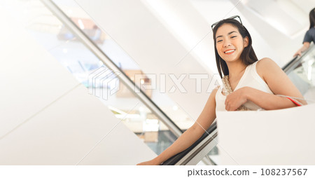 Asian woman happy face standing on escalator with shopping bags in department store city lifestyles 108237567