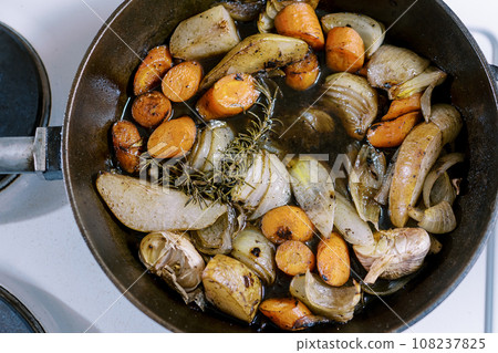 Chopped vegetables with spices are stewed in a frying pan on the stove. Top view Chopped vegetables with spices are stewed in a frying pan on the stove. Top view 108237825