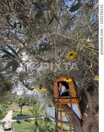 Smiling girl sitting in a wooden treehouse Smiling girl sitting in a wooden treehouse 108238332