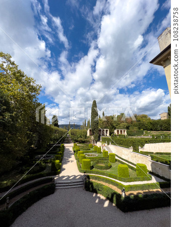 Decoratively trimmed bushes in the garden near an old mansion Decoratively trimmed bushes in the garden near an old mansion 108238758