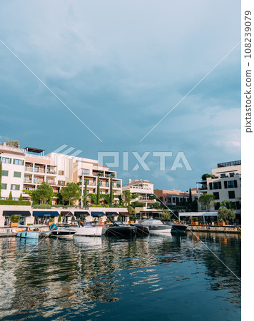 Motor yachts are moored along the shore with colorful hotels and expensive shops. Porto, Montenegro 108239079