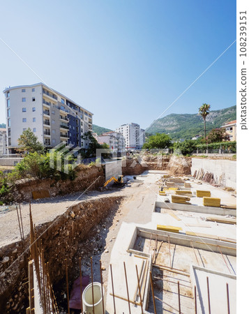 Excavator works at a construction site next to the frames for pouring the foundation 108239151