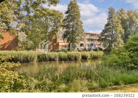 some trees and buildings by the water's edge with blue skies in the background, on a sunny day some trees and buildings by the water's edge with blue skies in the background, on a sunny day 108239322