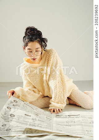 Woman sitting on the floor and reading a newspaper Woman sitting on the floor and reading a newspaper 108239692
