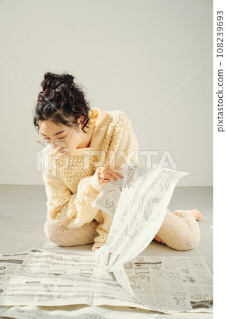 Woman sitting on the floor and reading a newspaper 108239693