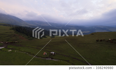 Pink-purple sunset in mountains with green fields Pink-purple sunset in mountains with green fields 108240980