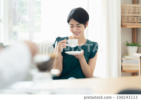 Women drinking coffee while having a conversation in the living room Women drinking coffee while having a conversation in the living room 108243113