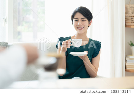 Women drinking coffee while having a conversation in the living room 108243114