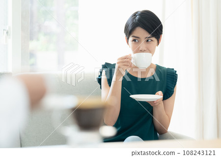 Women drinking coffee while having a conversation in the living room 108243121