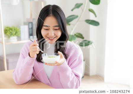 Young woman eating yogurt 108243274