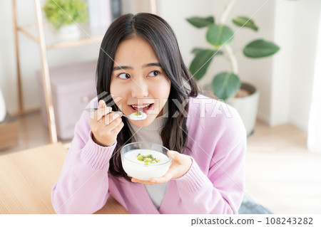 Young woman eating yogurt Young woman eating yogurt 108243282
