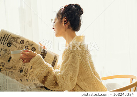 A woman chatting while reading a newspaper at a cafe A woman chatting while reading a newspaper at a cafe 108243384