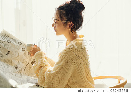 一位女士在咖啡館一邊看報紙一邊聊天 一位女士在咖啡館一邊看報紙一邊聊天 108243386