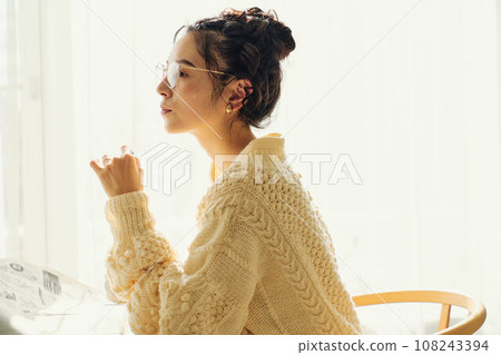 A woman chatting while reading a newspaper at a cafe A woman chatting while reading a newspaper at a cafe 108243394