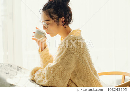 一位女士在咖啡館一邊看報紙一邊聊天 108243395