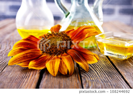 Organic sunflower oil in a small glass jar with sunflower seeds and fresh flowers. Outdoors 108244692