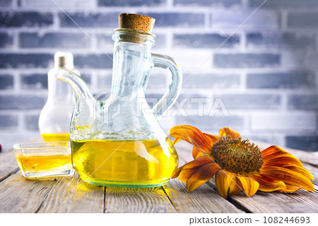 Organic sunflower oil in a small glass jar with sunflower seeds and fresh flowers. Outdoors Organic sunflower oil in a small glass jar with sunflower seeds and fresh flowers. Outdoors 108244693