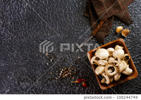 Raw mushrooms champignons on black background, cooking fresh champignons Raw mushrooms champignons on black background, cooking fresh champignons 108244749