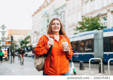 Young beautiful woman with coffee walking in street. Take away or delivery concept. Copy space. Autumn lifestyle. Young beautiful woman with coffee walking in street. Take away or delivery concept. Copy space. Autumn lifestyle. 108245861