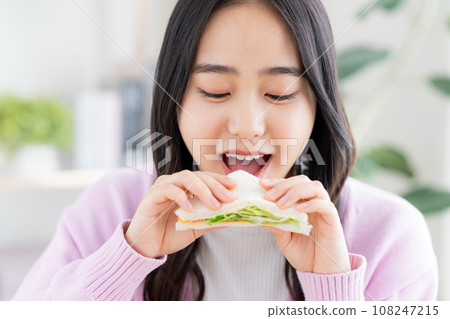 Young woman eating a sandwich 108247215