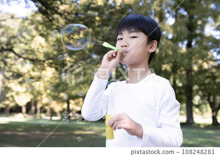 Boy making soap bubbles in the park 108248281