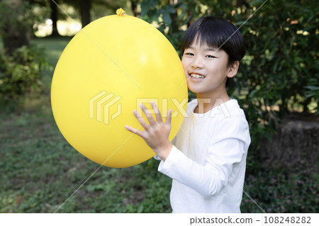 Boy smiling and holding a yellow balloon Boy smiling and holding a yellow balloon 108248282