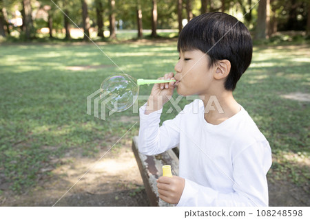 Boy making soap bubbles in the park 108248598