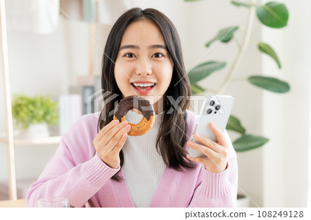 A young woman eating a donut A young woman eating a donut 108249128
