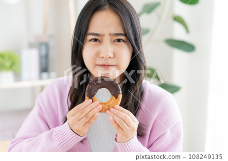 A young woman eating a donut 108249135
