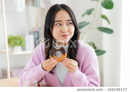 A young woman eating a donut 108249137
