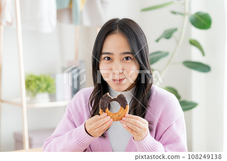 A young woman eating a donut 108249138