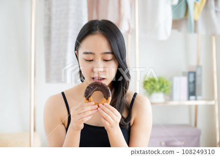 A young woman eating a donut A young woman eating a donut 108249310