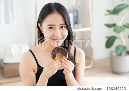 A young woman eating a donut 108249313
