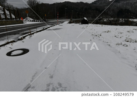 Scenery of a parking lot covered in snow next to a slippery road Scenery of a parking lot covered in snow next to a slippery road 108249579