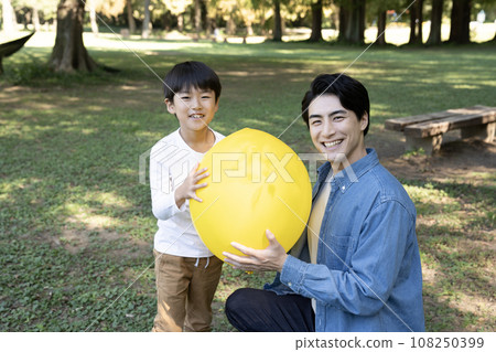 Parent and child smiling and holding a yellow balloon Parent and child smiling and holding a yellow balloon 108250399
