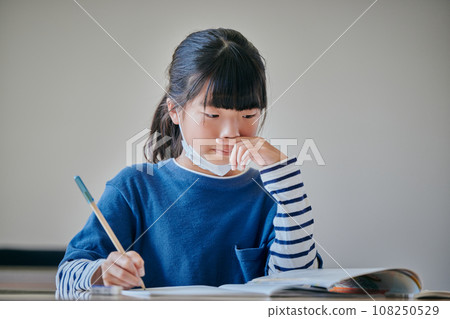 Elementary school girl who can't stop her runny nose and holds it with her hand Elementary school girl who can't stop her runny nose and holds it with her hand 108250529
