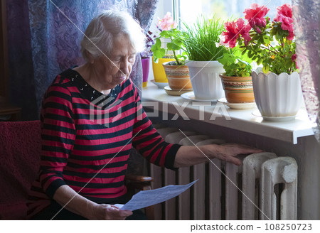 Woman holding cash in front of heating radiator. Payment for heating in winter. Selective focus. Woman holding cash in front of heating radiator. Payment for heating in winter. Selective focus. 108250723