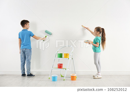 Little children painting on blank white wall indoors 108252012